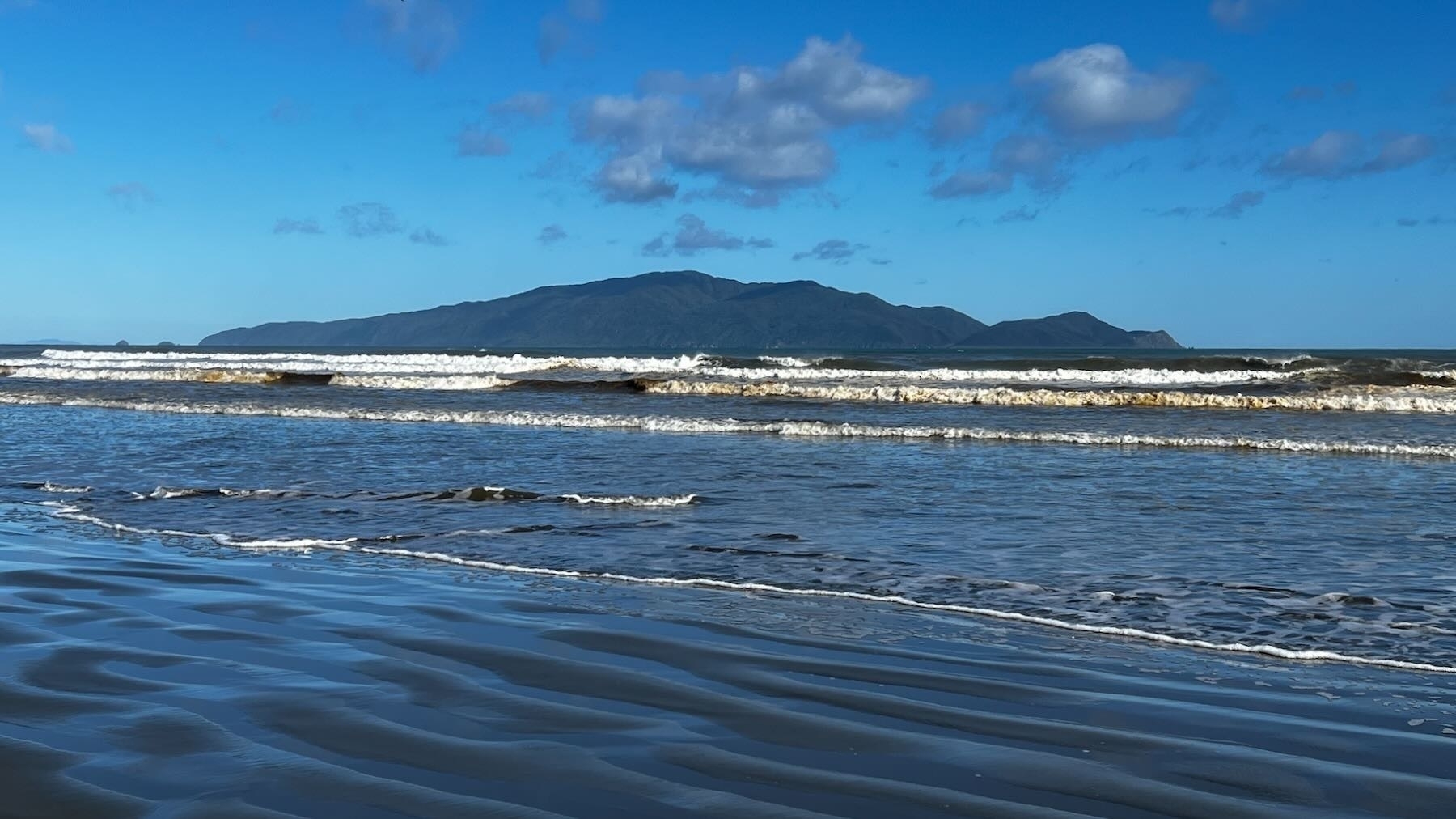 Small waves at Peka Peka Beach with Kāpiti Island in the background.
