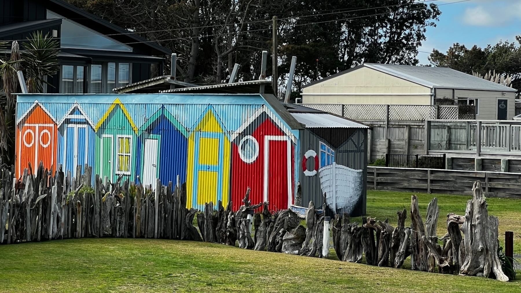 Shed painted to resemble a row of beach-side doorways, with boat. 