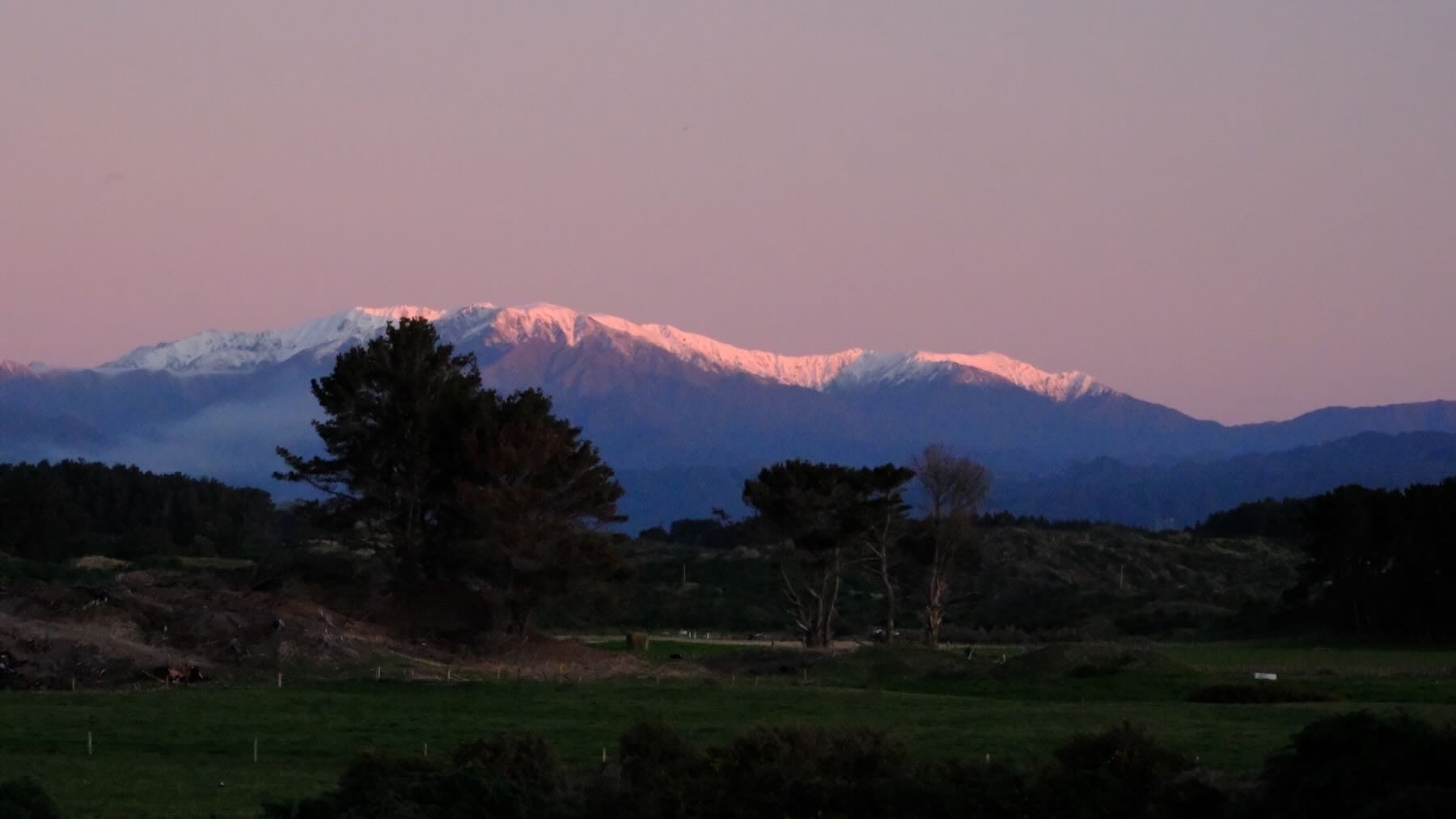 Snowy mountains at sunset, with a red tinge to the snow.