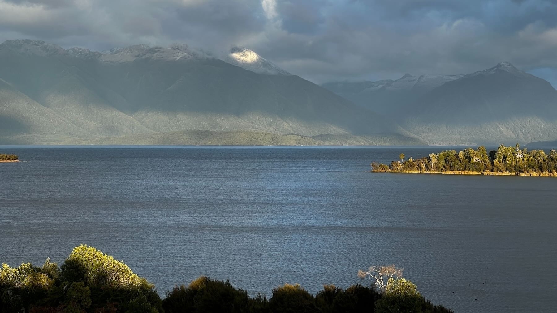 Te Anau Downs Scenic Lookout looks over the lake to mountains beyond, with a snowy peak. 