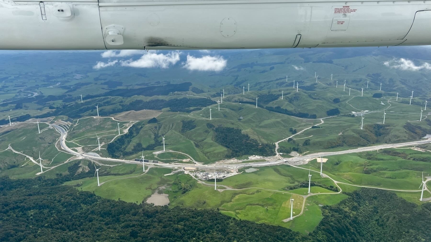 Wind farm amongst green paddocks as seen from a plane.