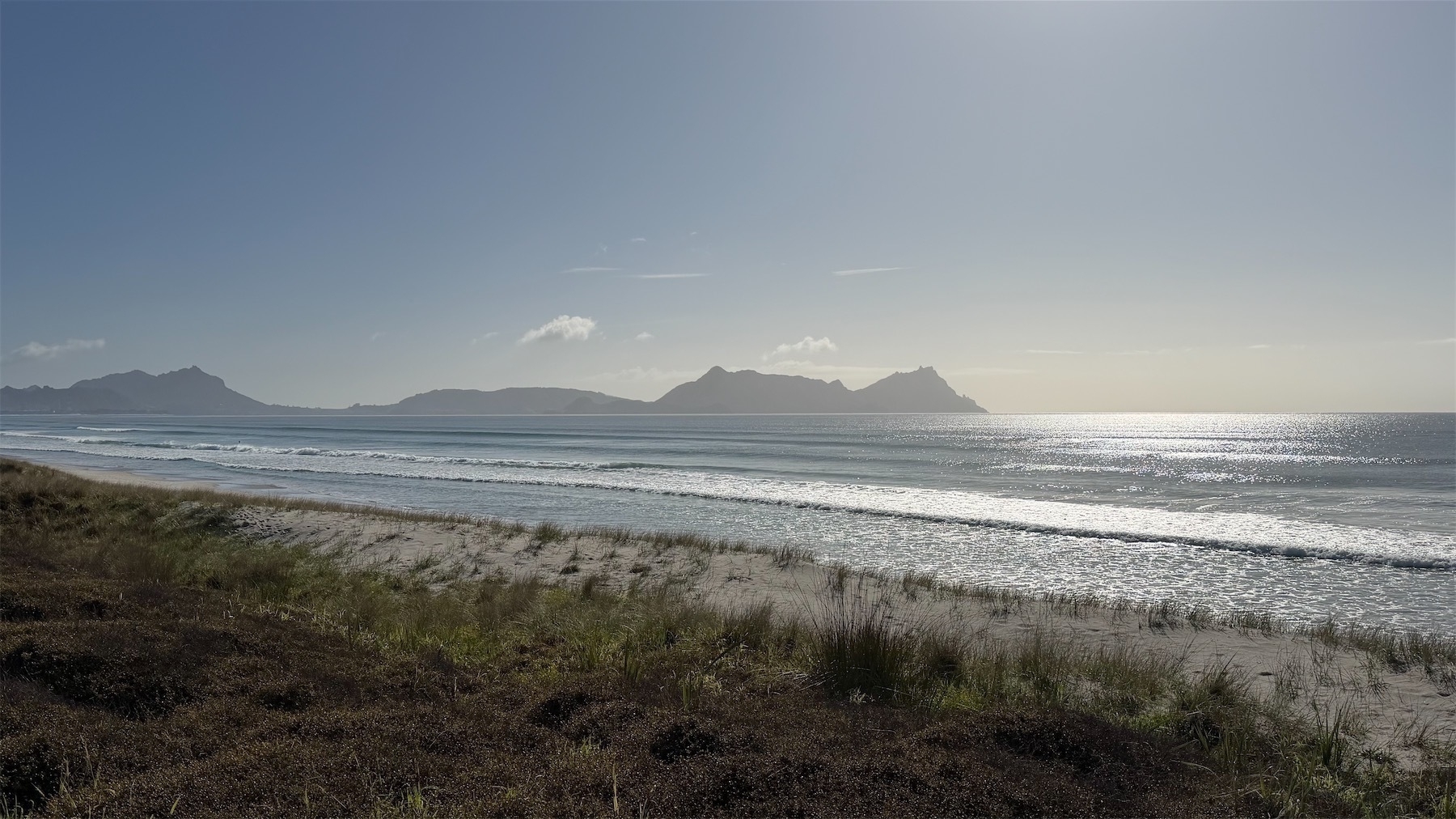 An expanse of shining sea, with hills behind.