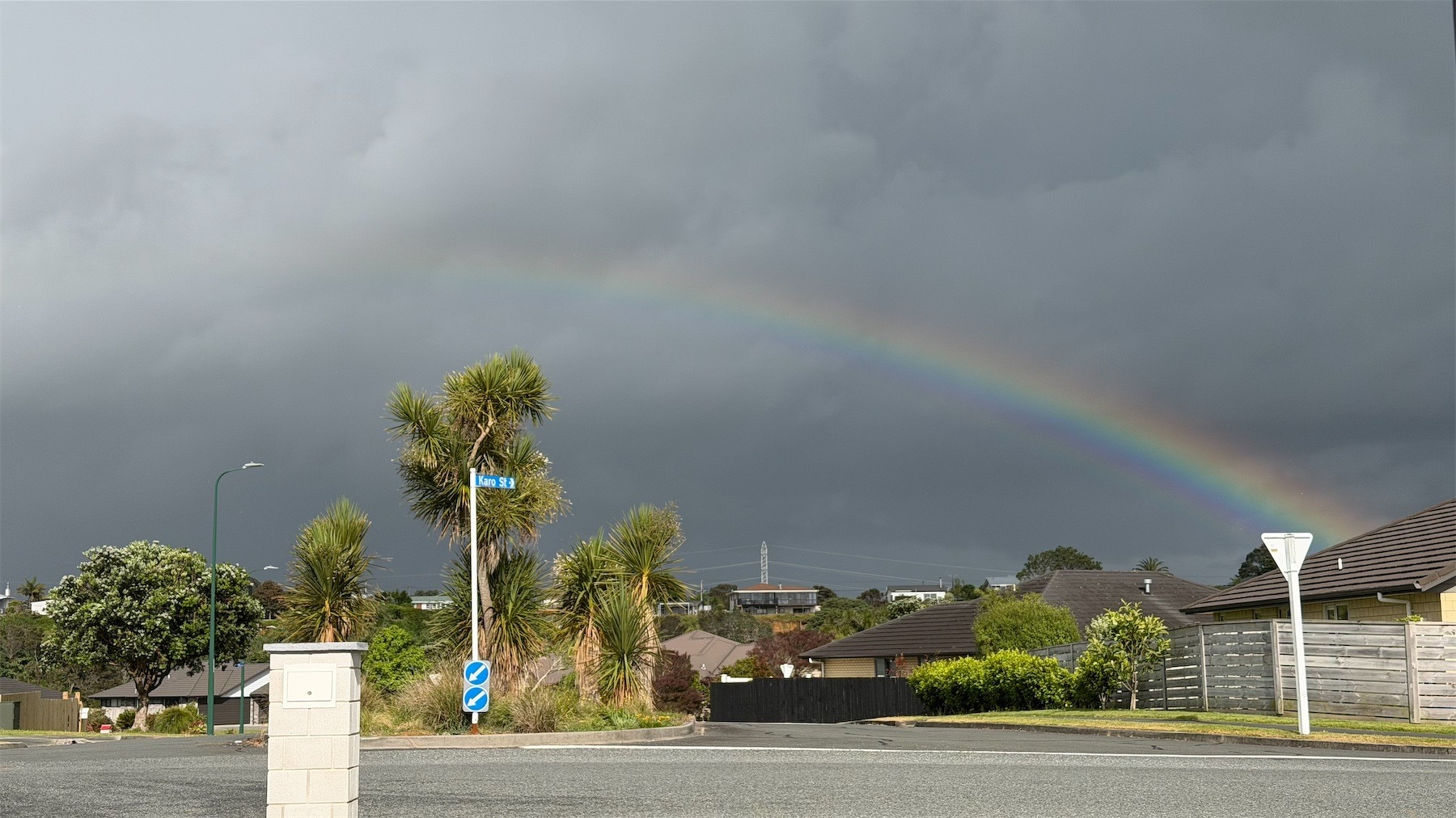 Partial rainbow against a dark sky with street scene in the foreground.