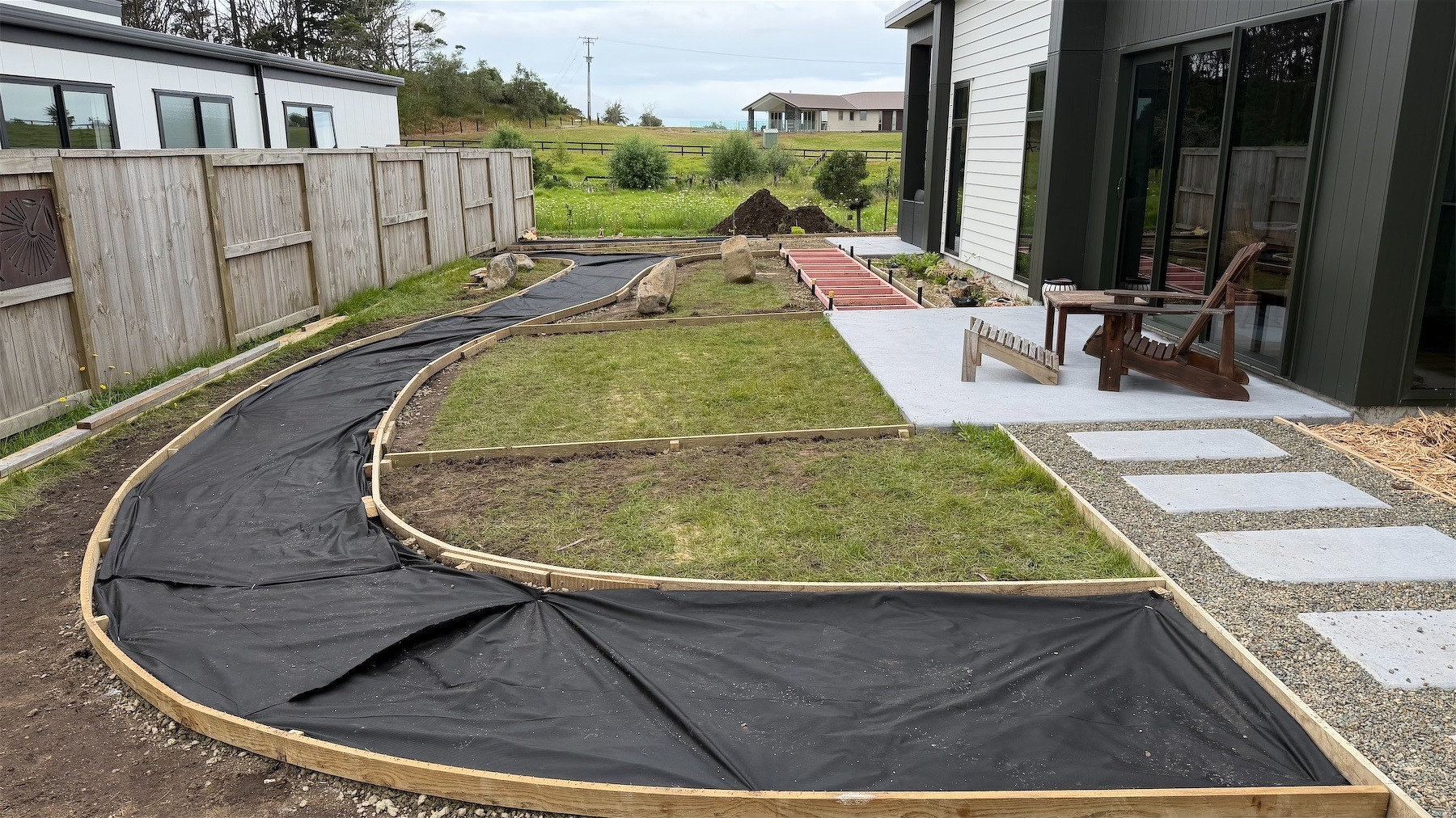 Wooden boards and weedmat define paths and planted areas.