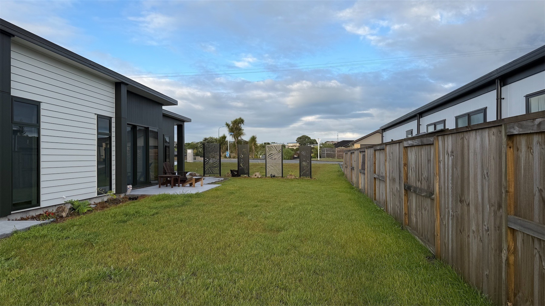 A small expanse of grass, with privacy panels at the far end.