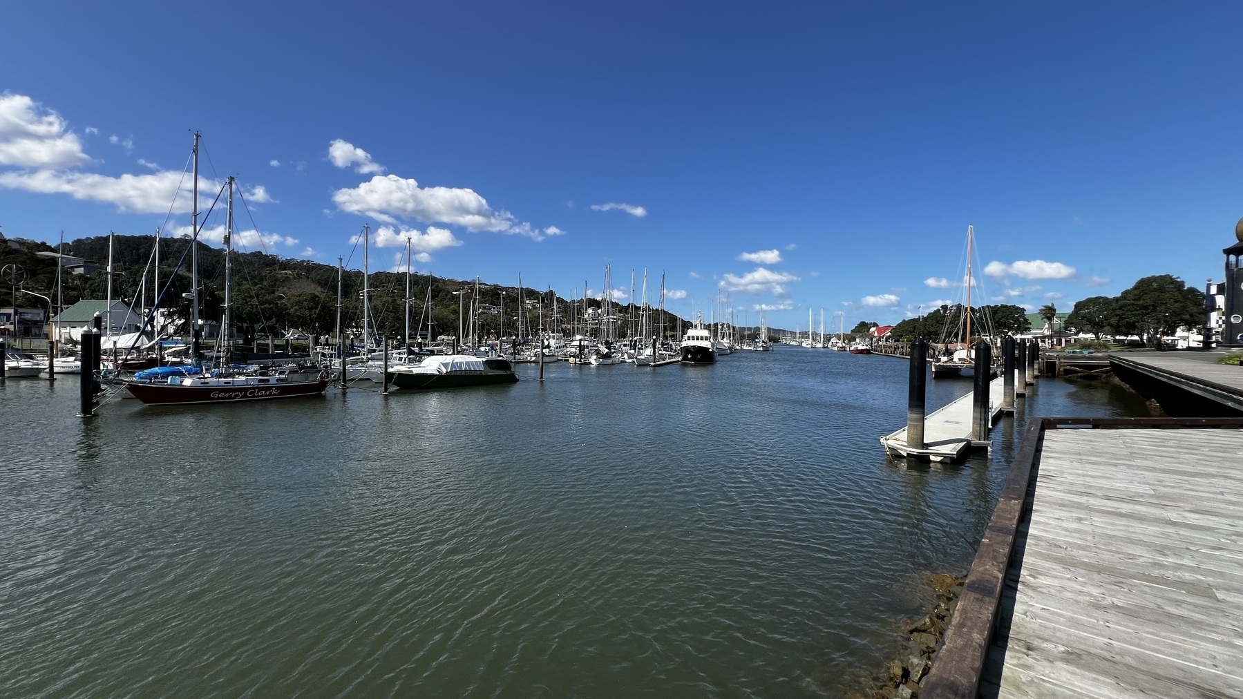  A marina is filled with numerous sailboats and yachts under a bright blue sky with a few clouds.