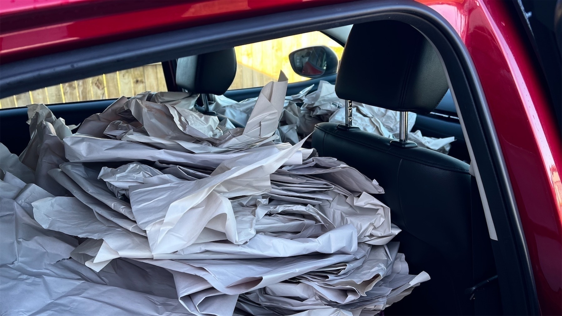Car back seat and front passenger seat loaded with packing paper. 