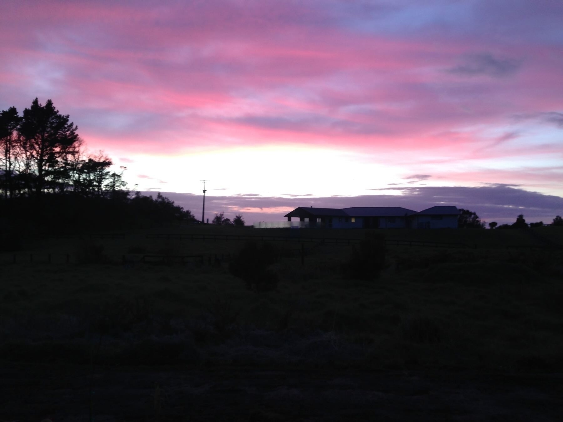 Sunrise - pink sky above dark land.