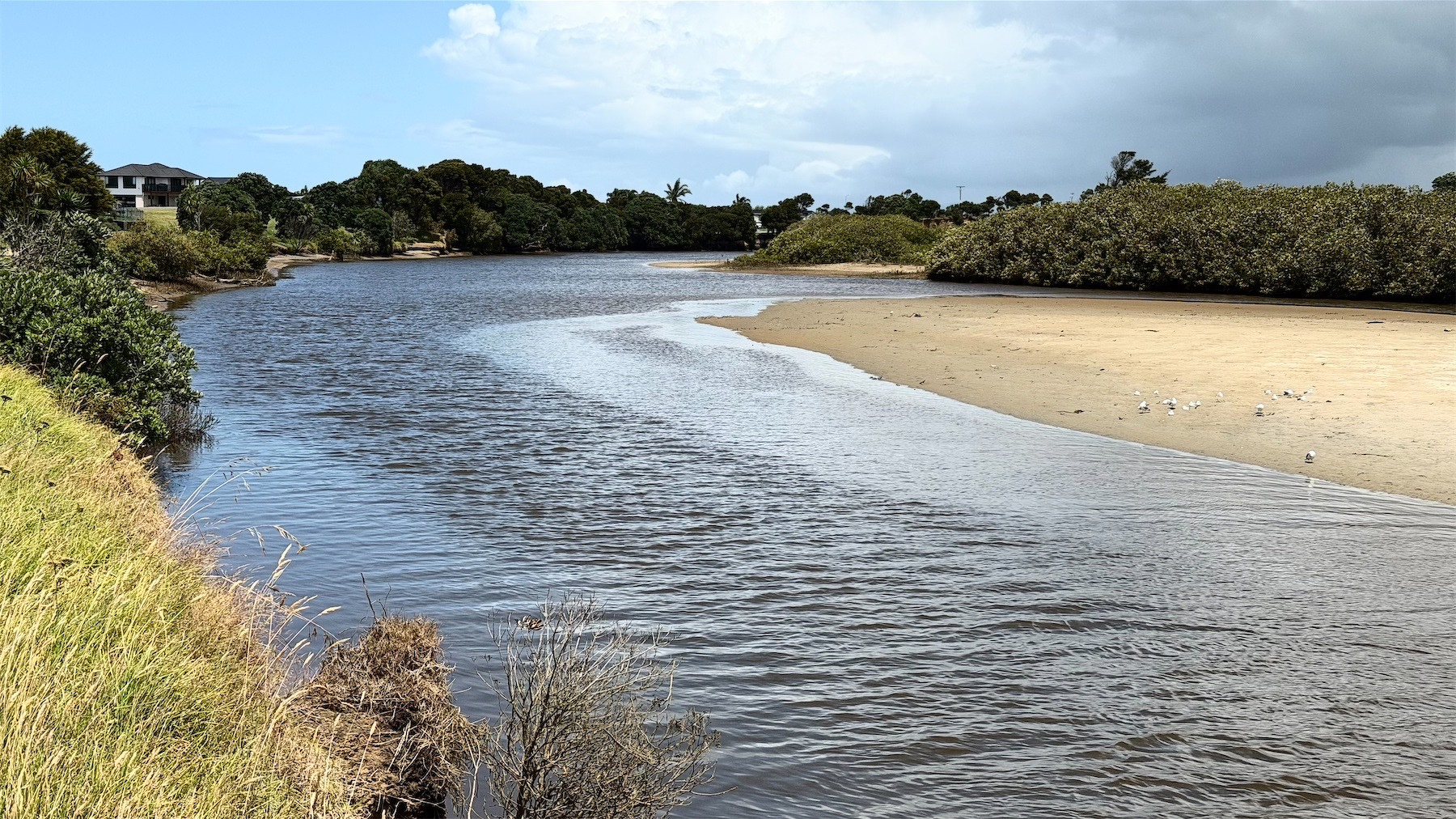 River with sand bar between green banks.