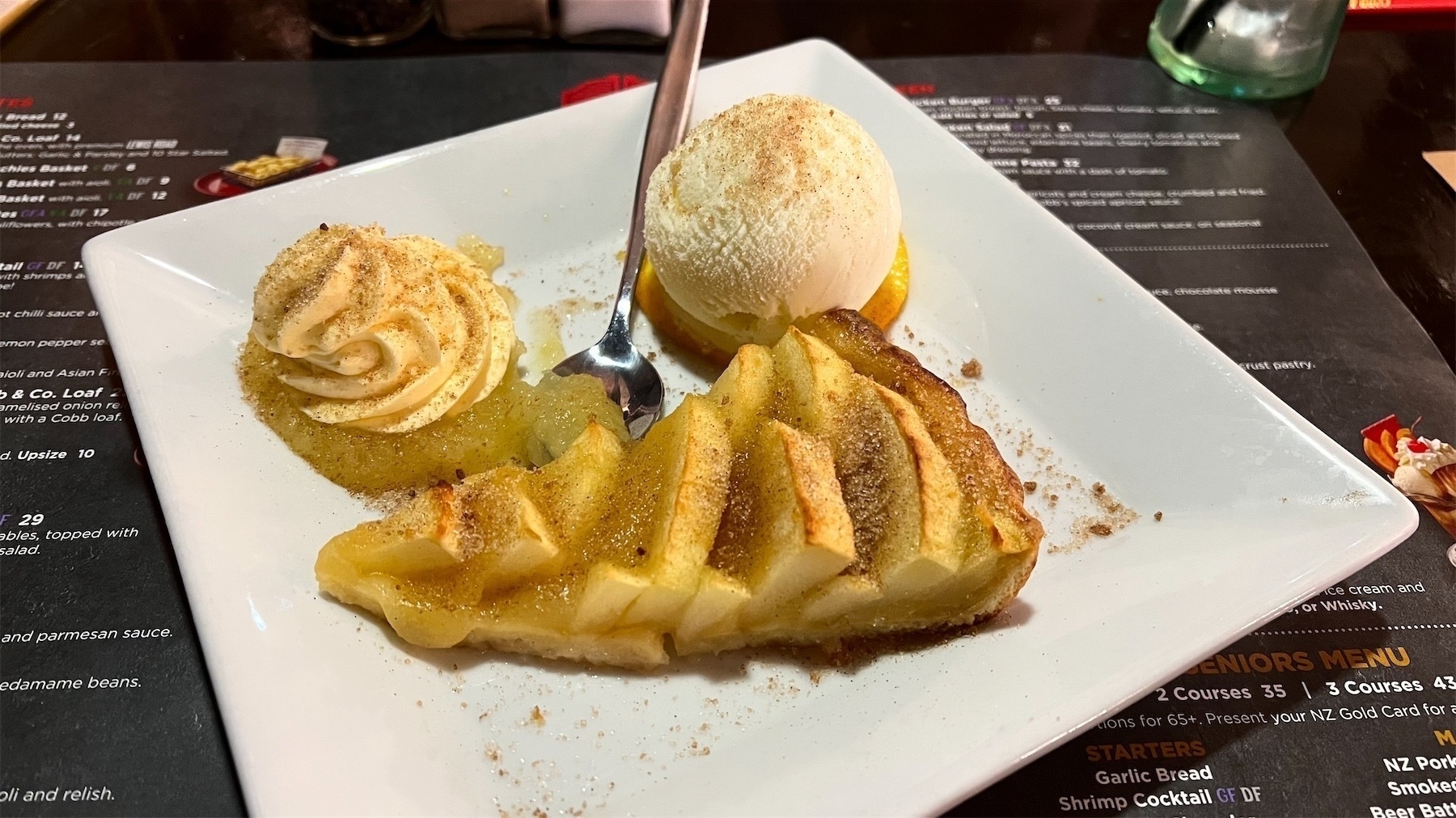 A plate of apple tart with ice cream, cream and apple sauce.