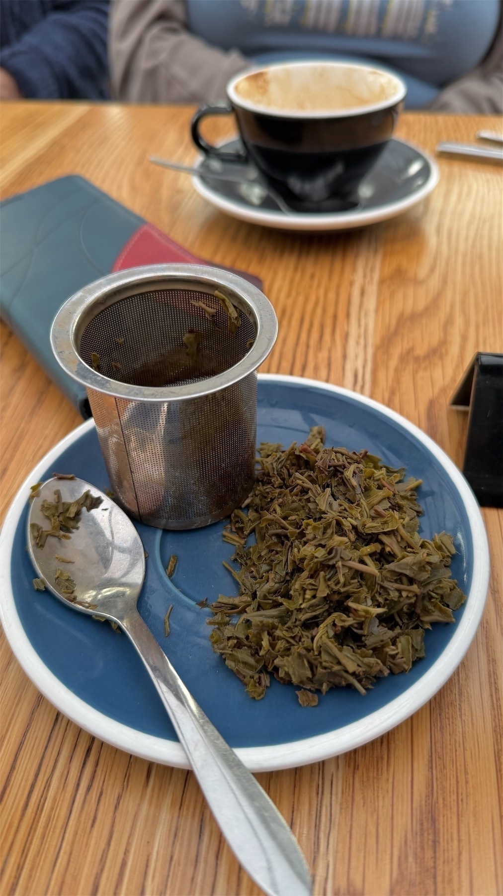 A saucer half-covered in a pile of green tea leaves. 