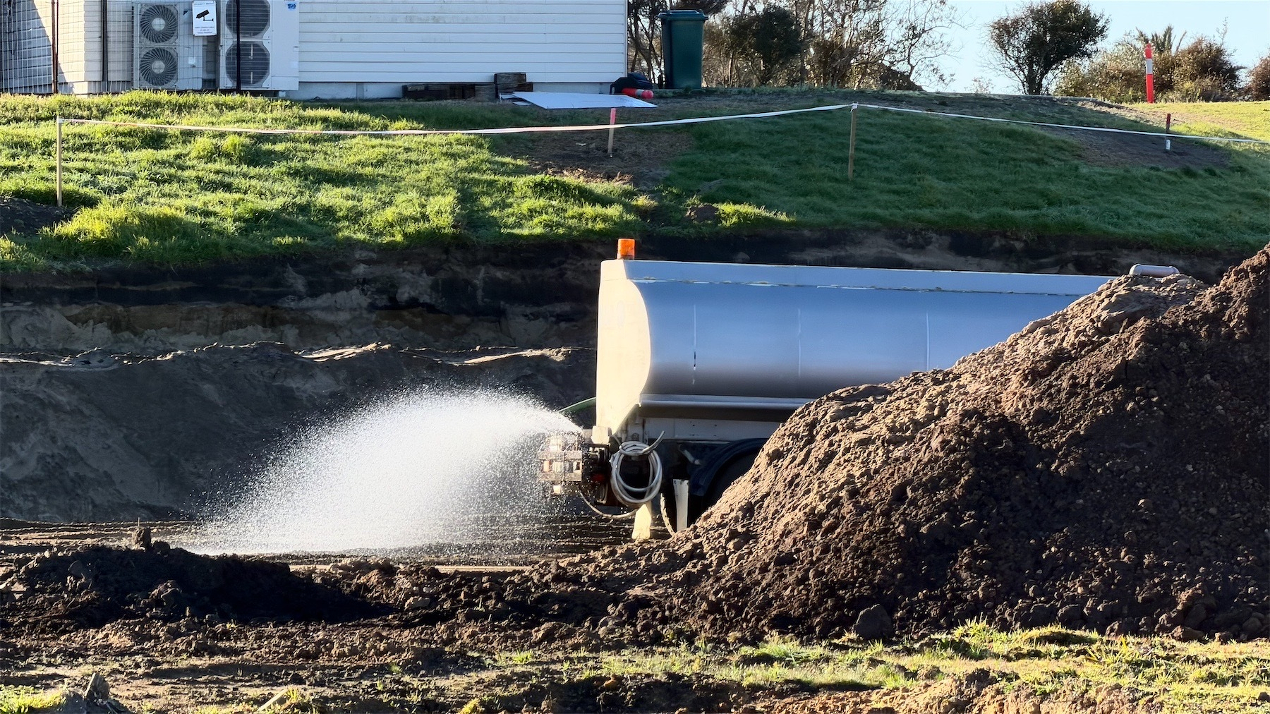 Tanker sprinkles water on the ground. 