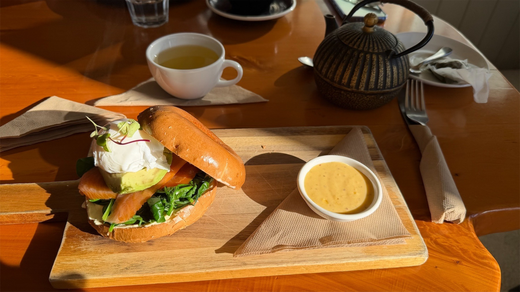 Loaded bagel, with teacup behind.