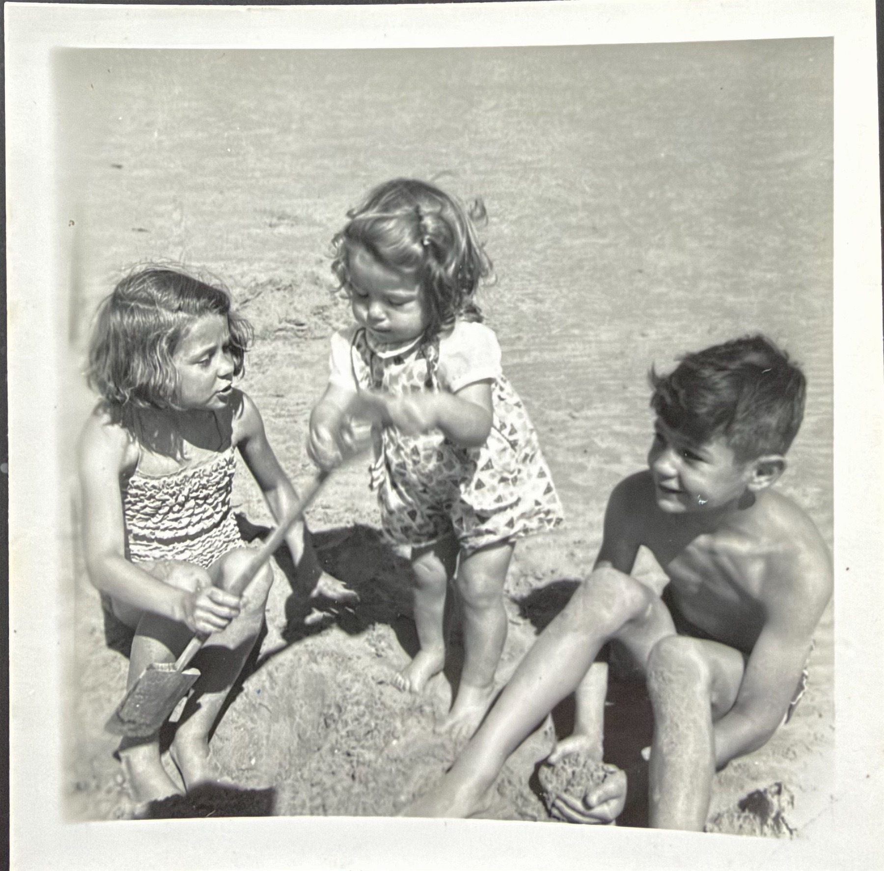 Three children on a sandy beach.