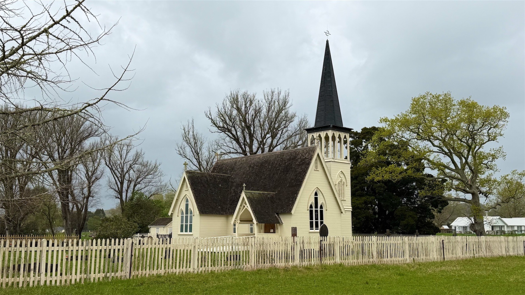 Small white church with steep dark roof and a tower with a very steep spire.