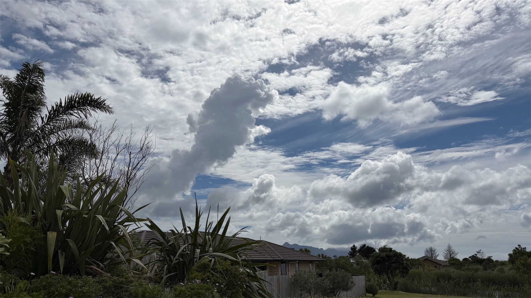 High white clouds with a finger-like dark cloud below them. 
