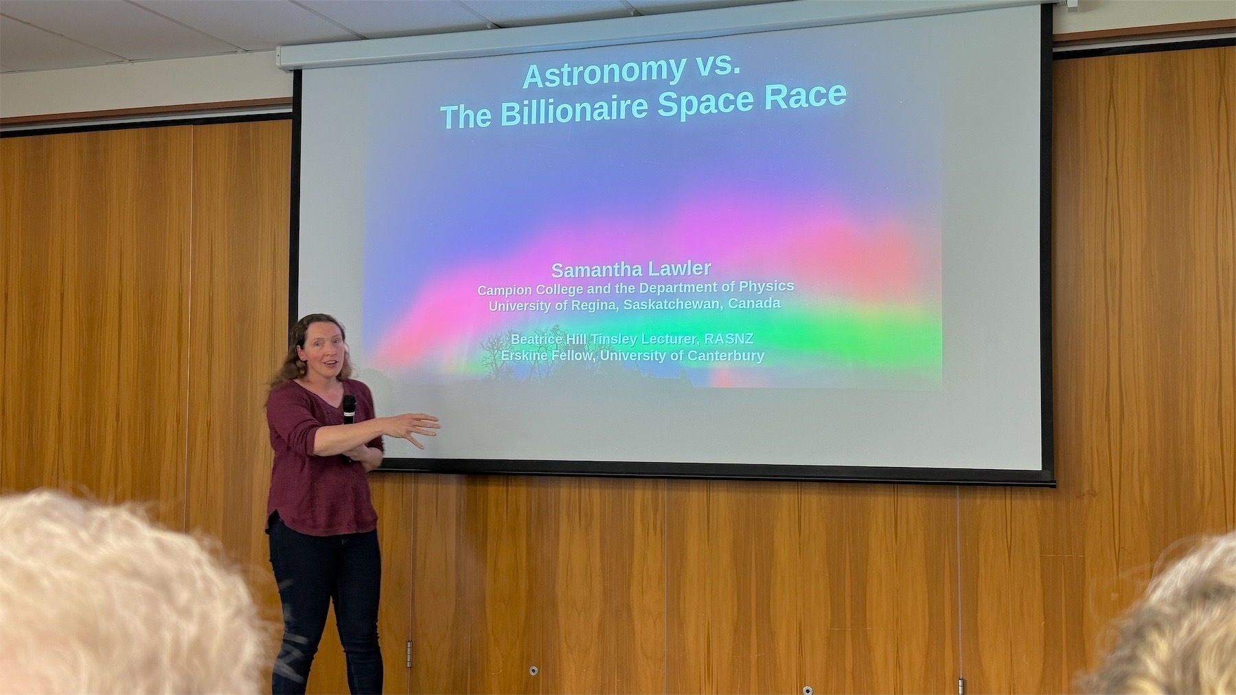 Dr Samantha Lawler in front of a title slide for her talk.