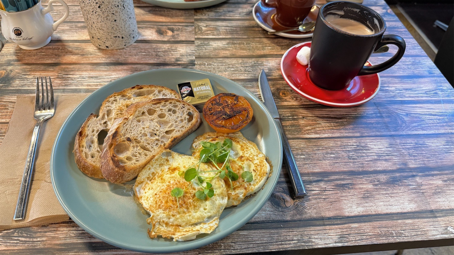 Fried eggs over easy with tomato and toast.