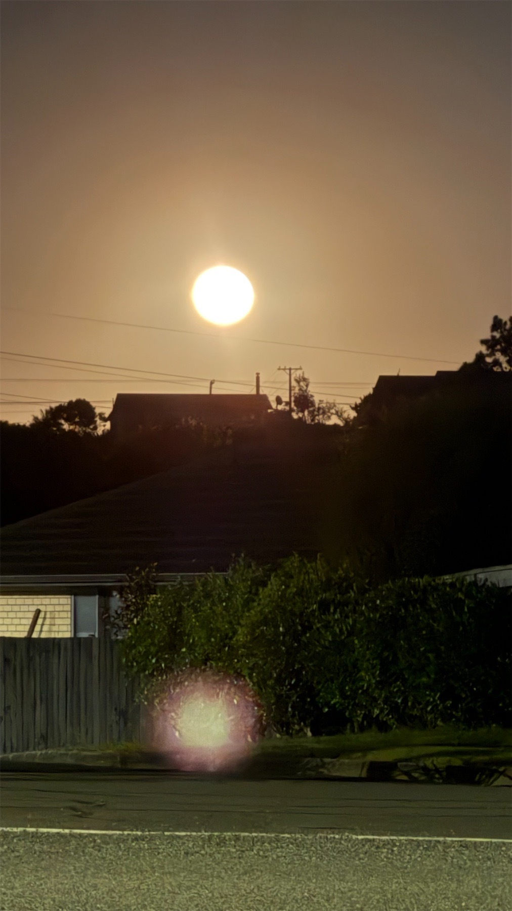 Full moon above dark silhoettes of houses.