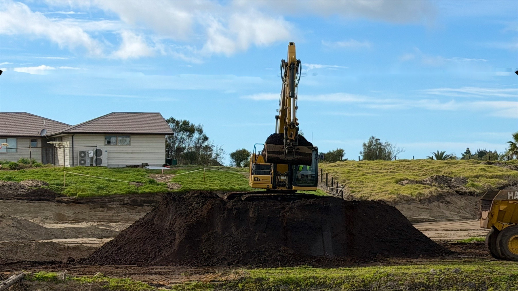 A digger atop a large mound of soil. 