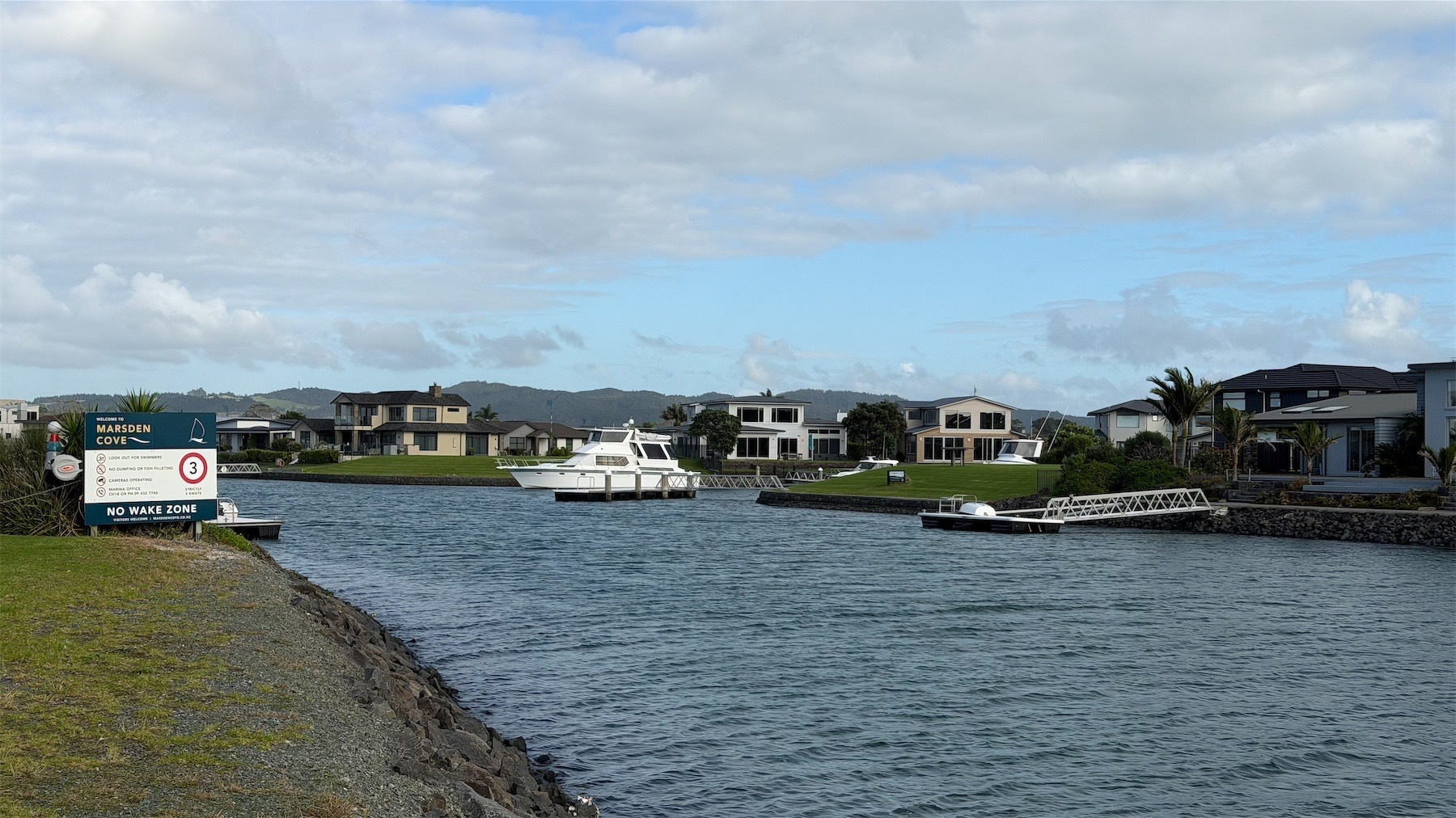 Entrance to the marina where some houses have private jetties, with one large boat in evidence. 