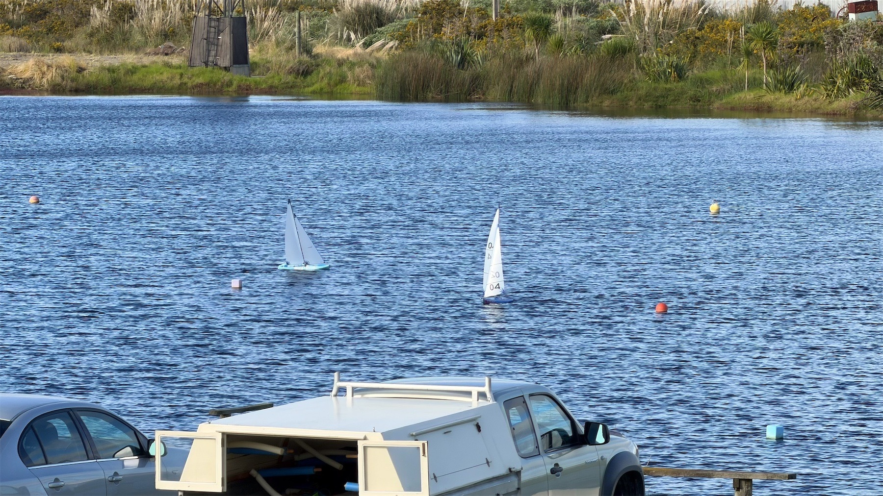 Two model boats sail a course on a small lake.