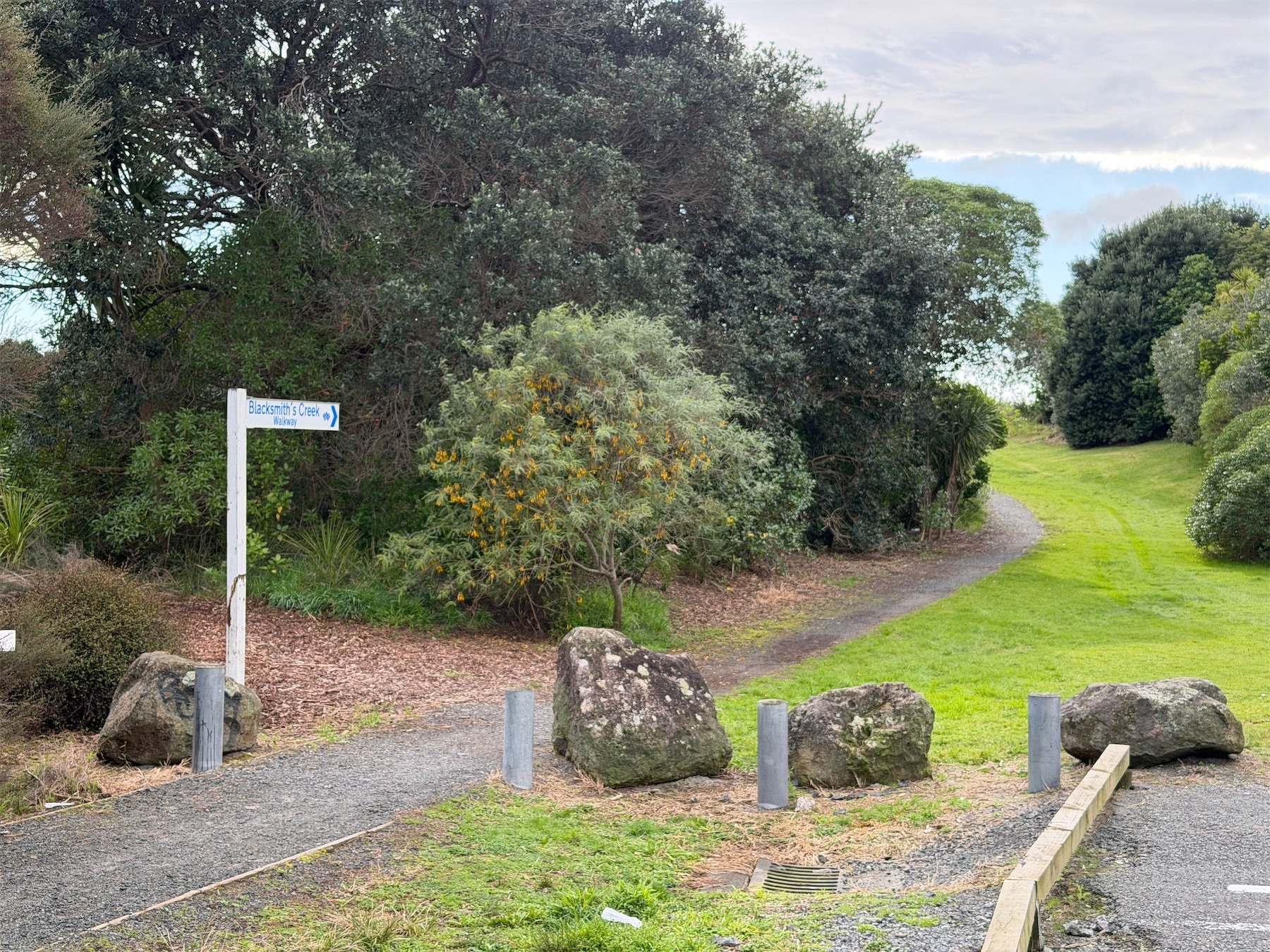 Sign points to the grassy walk between trees. 