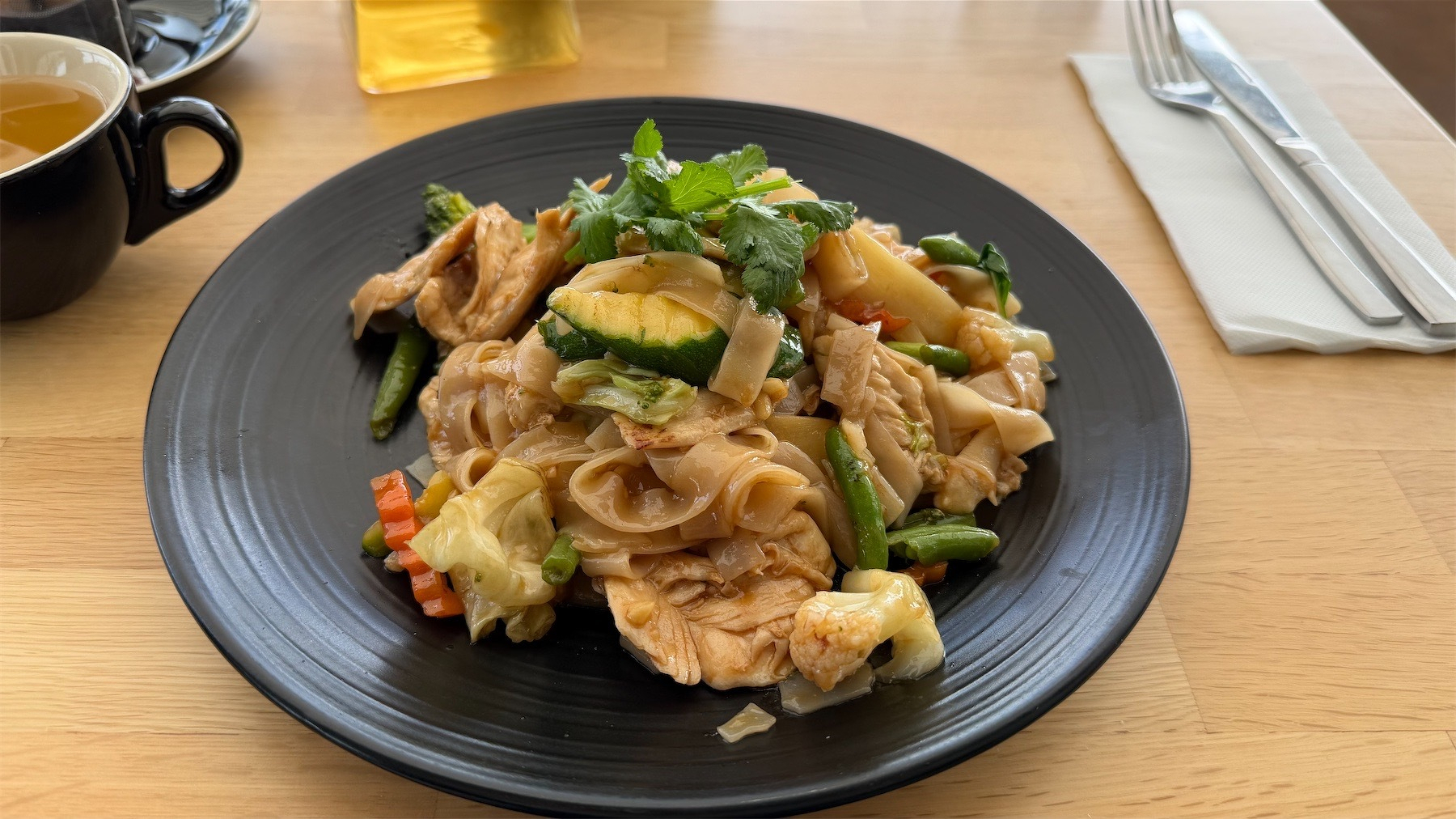 Thai meat, veg and noodles on a dark plate. 