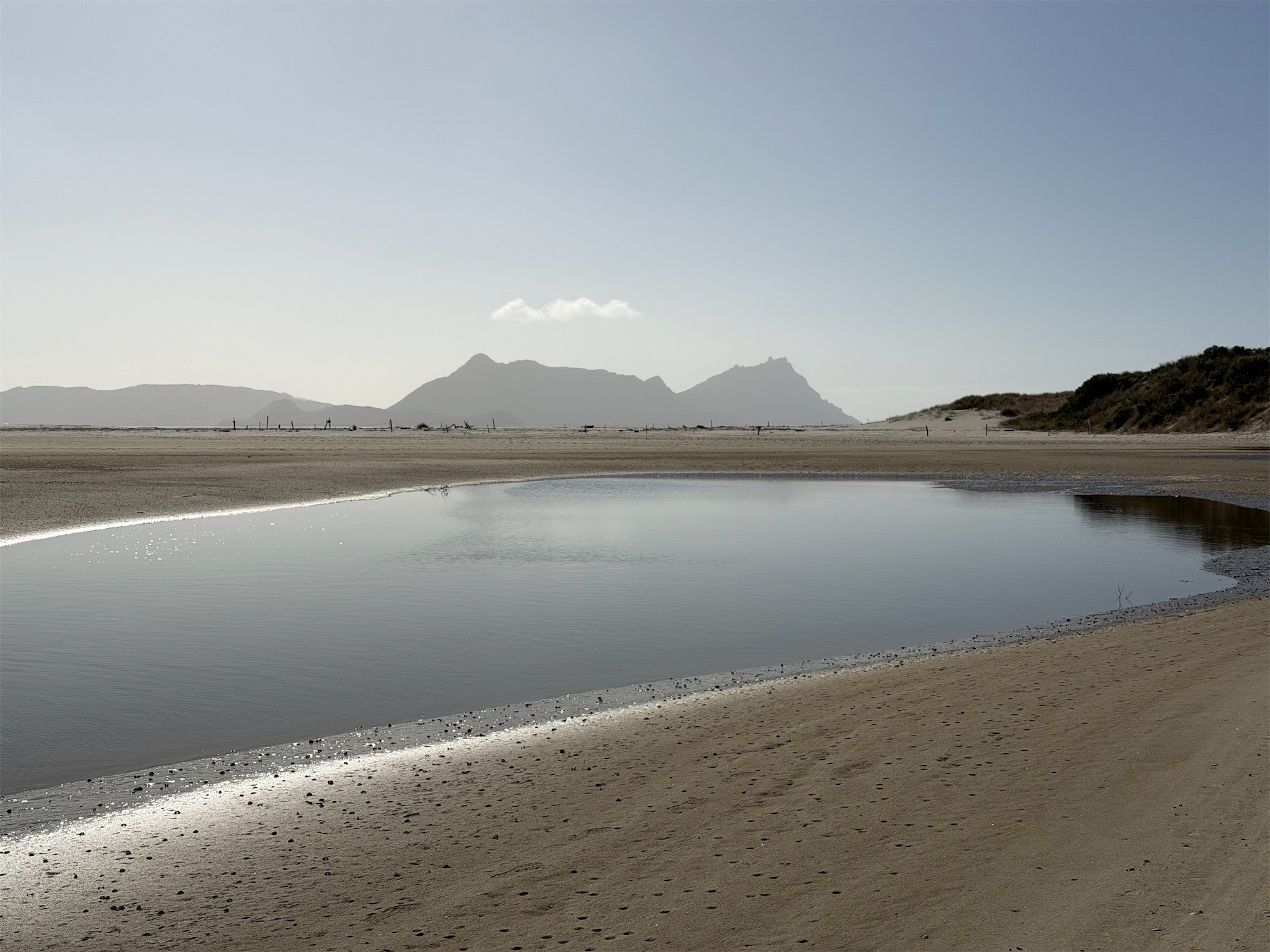 View across river mouth with sandy banks to mountain beyond. 