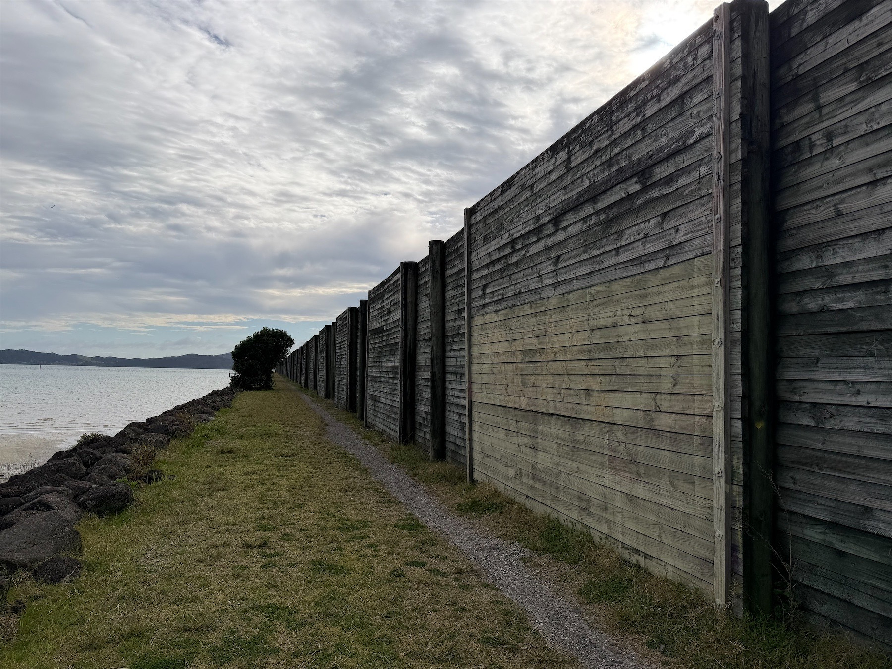 High wooden fence and sea. 