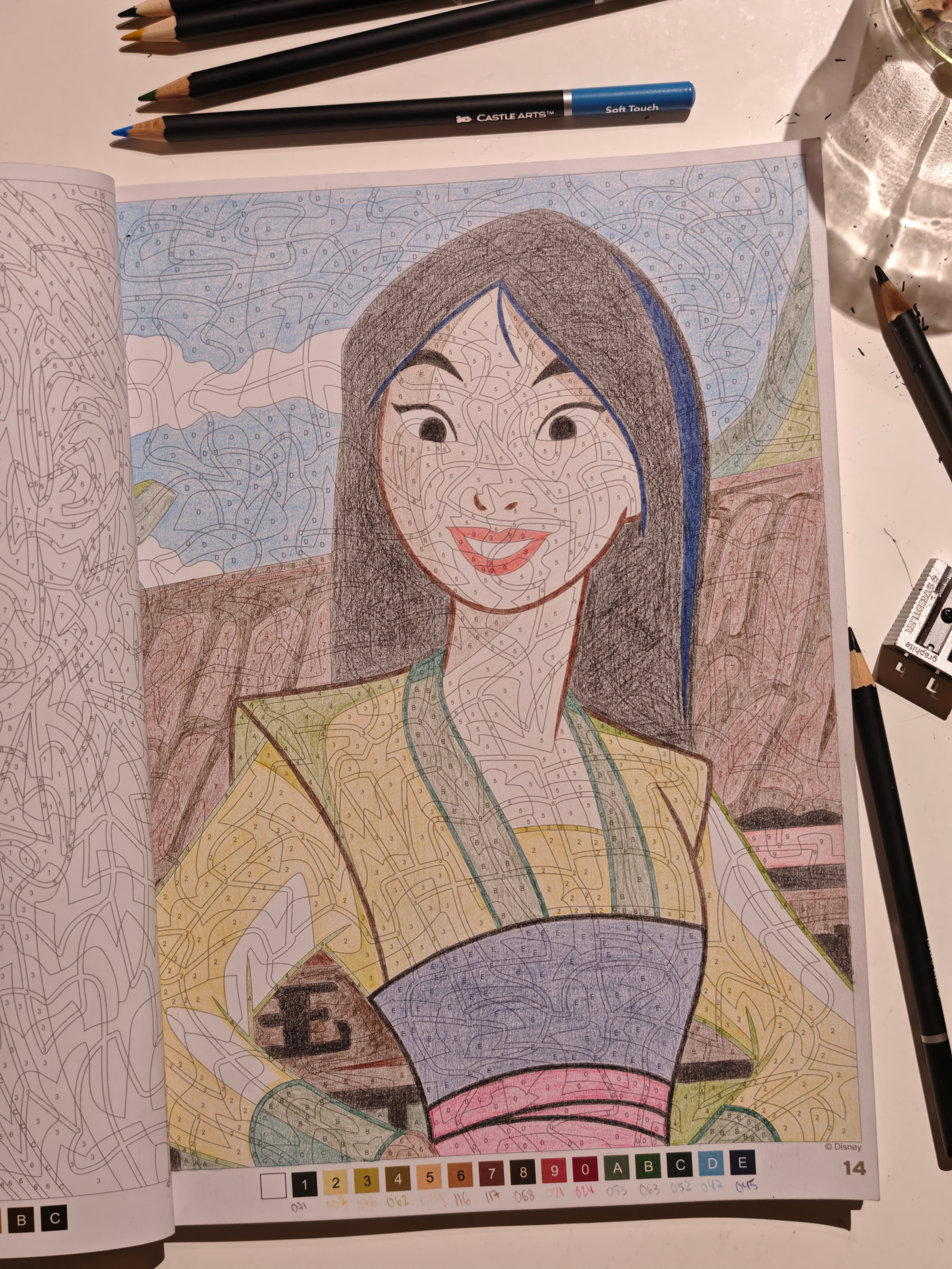A color-by-numbers page depicts a drawing of Mulan, partially colored with pencils scattered around.