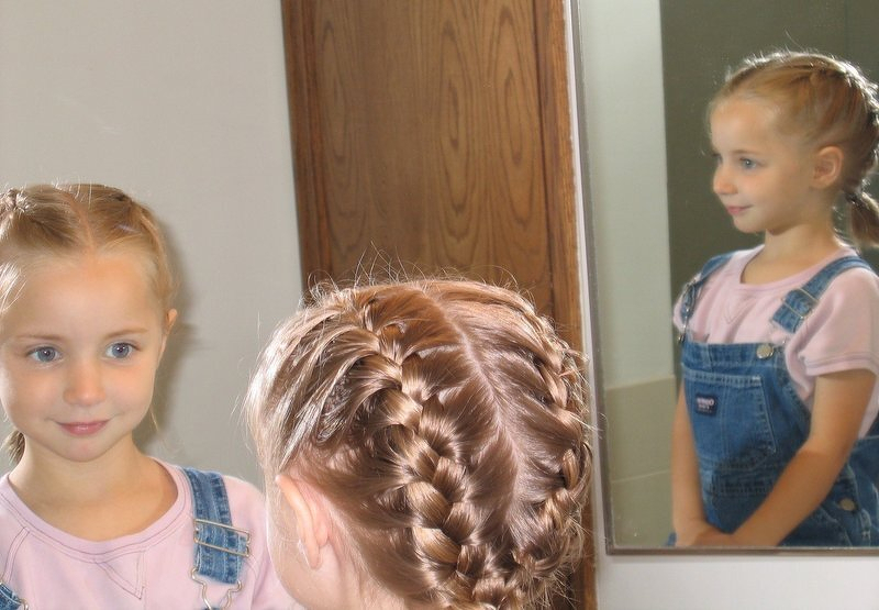 Kaylee with her hair braided for the first time, reflected in a mirror