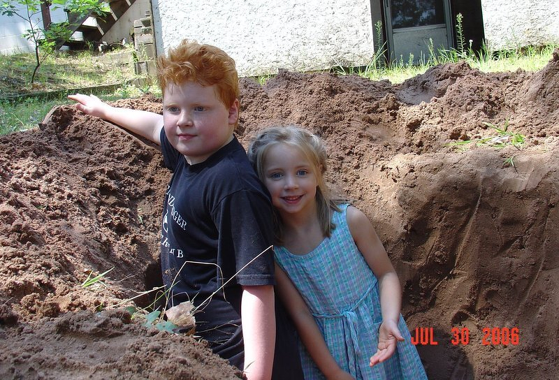 Spencer and Kaylee standing in the giant hole they dug behind Grandma and Grandpa's house