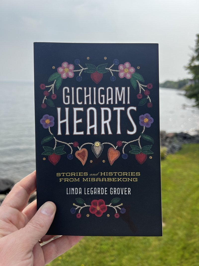 Gichigami Hearts by Linda LeGarde Grover, held up in front of Lake Superior