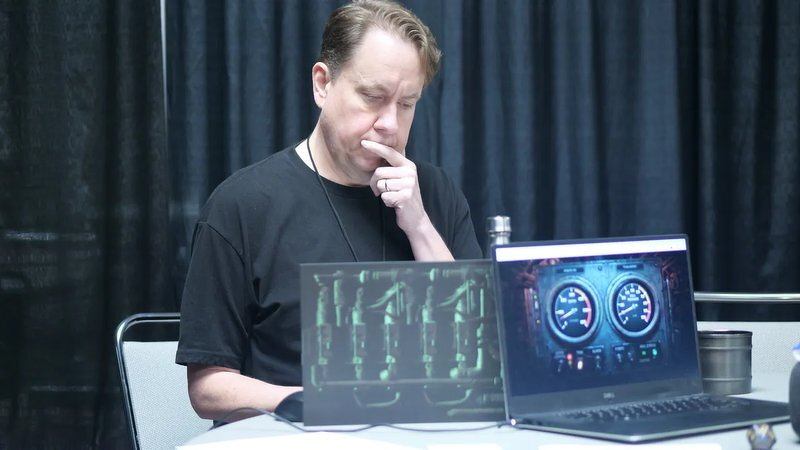 Justin behind the GM screen at Excalibur Con, hand on his chin, two laptops in front of him showing the ship's readouts