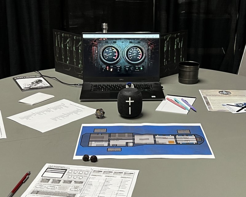 The Mothership table from above: character sheets, dice, a deck plan of the Rimor 89, and a laptop displaying the ship's gauges