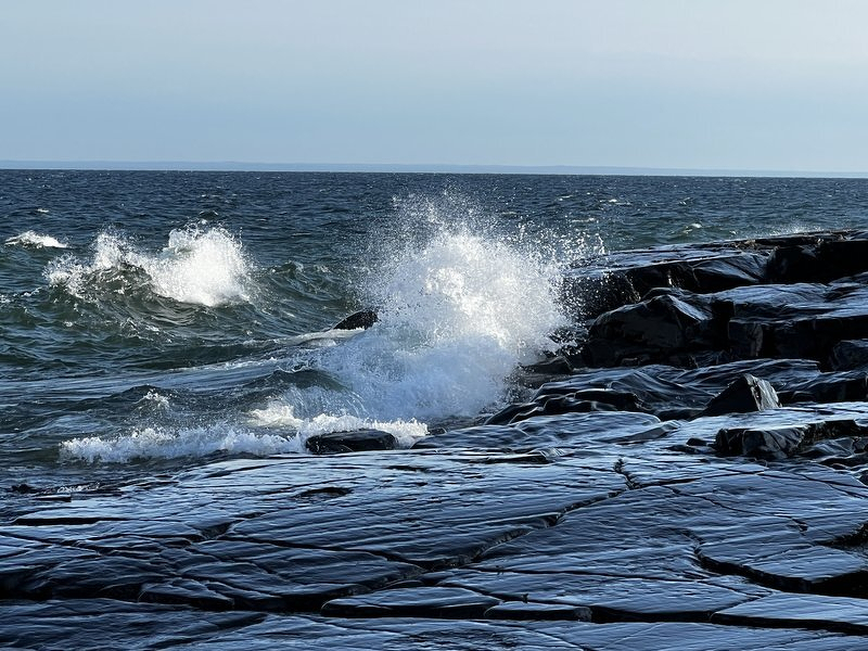 A wave breaking over the flat black basalt shelf at Stony Point