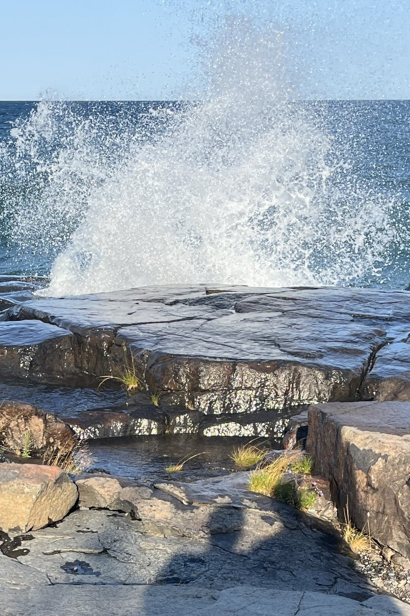 Spray from a big wave shooting into the air above the ledge rock at Stony Point