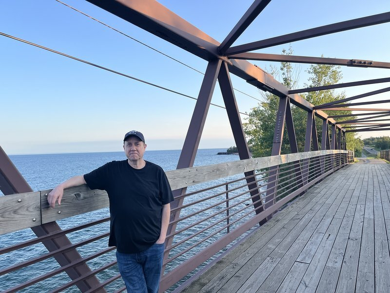 Justin leaning on the railing of the new bridge above Iona's Beach
