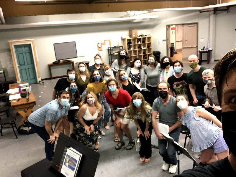 The masked Spamalot cast crowded together in the rehearsal room for a group photo