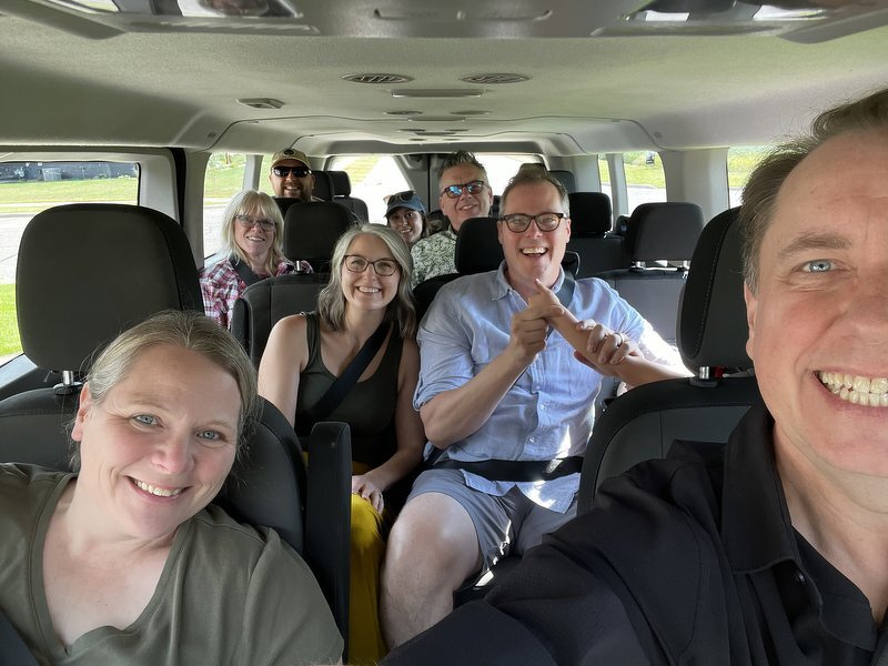 A van full of friends grinning for a selfie at the start of the drive to American Players Theatre