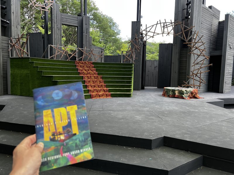 An APT program held up in front of the green ramp and branching orange set of As You Like It