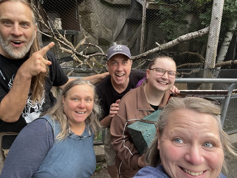 A group selfie at the zoo with Tom pointing at Archimedes the owl