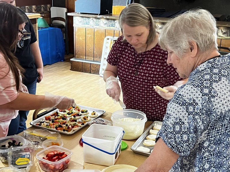 Family members assembling trays of appetizers in the hall kitchen