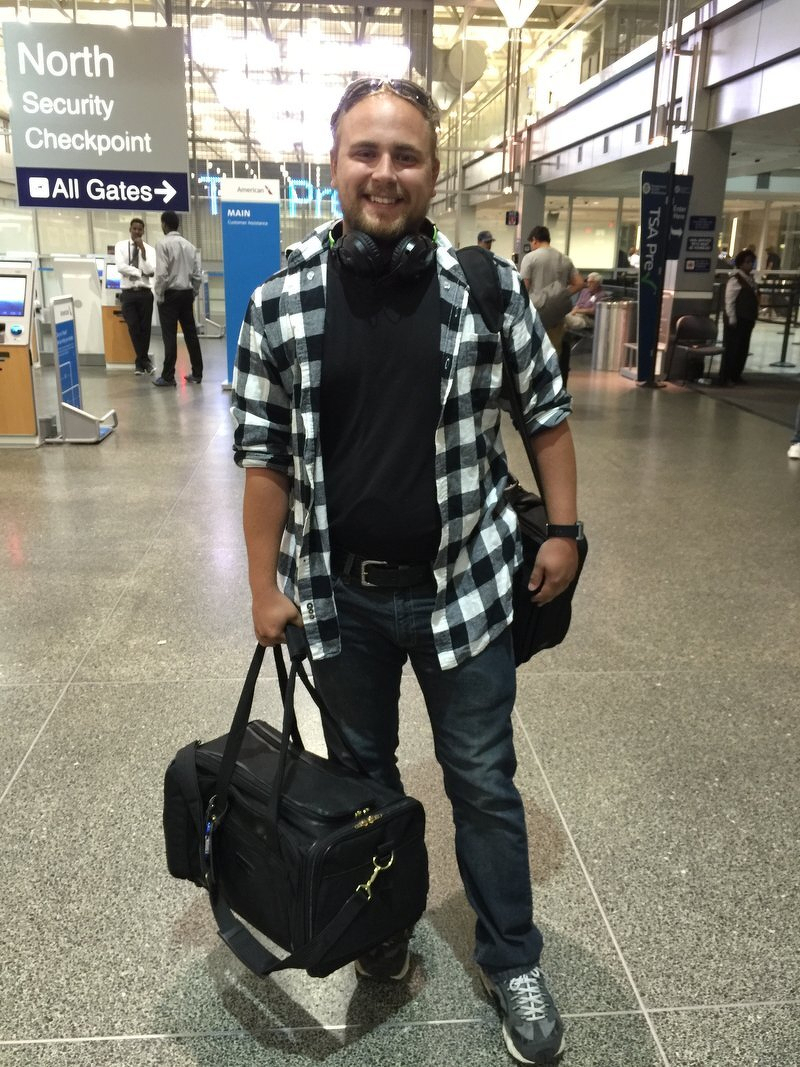 Alex at the airport security checkpoint with his duffel bag, headed to grad school in California