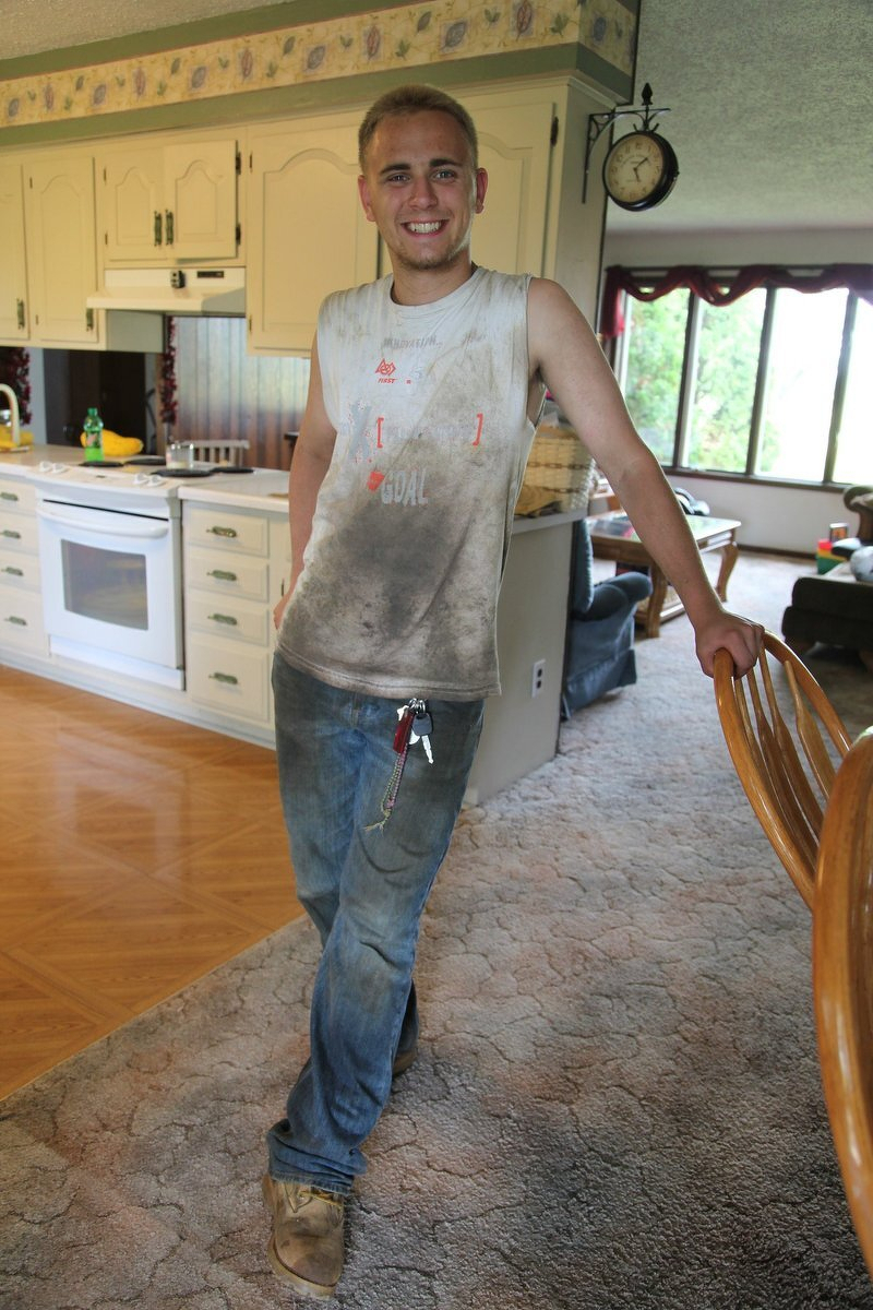 Alex in paint-spattered work clothes, grinning in the middle of a job with cousin Josh
