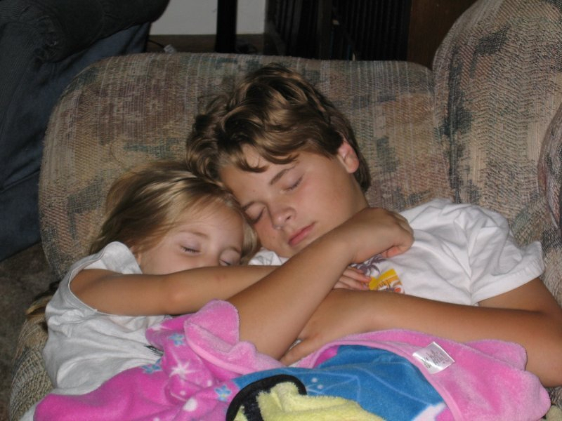 Corey asleep on the couch with his arm around Kaylee, both of them napping