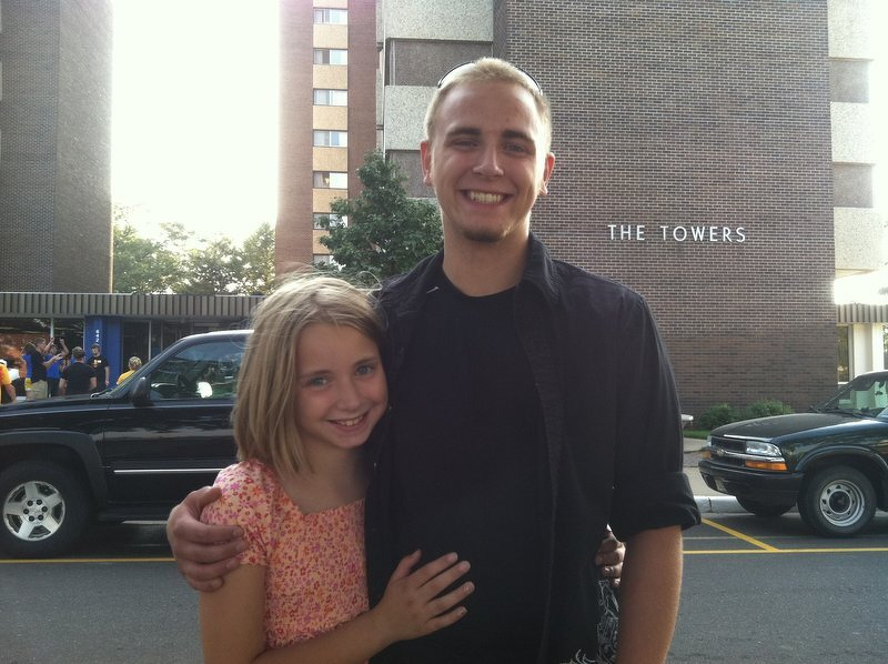 Alex with his arm around a young Kaylee in front of The Towers dorm in Eau Claire on move-in day