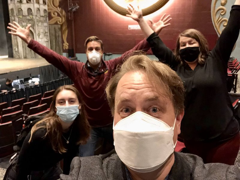 A masked selfie in the NorShor house with three members of the Spamalot team behind me, arms raised in celebration