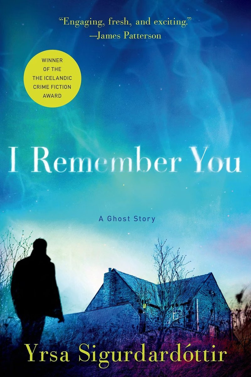 The cover of I Remember You: A Ghost Story by Yrsa Sigurðardóttir, with a silhouetted figure approaching a lonely house under a glowing blue sky